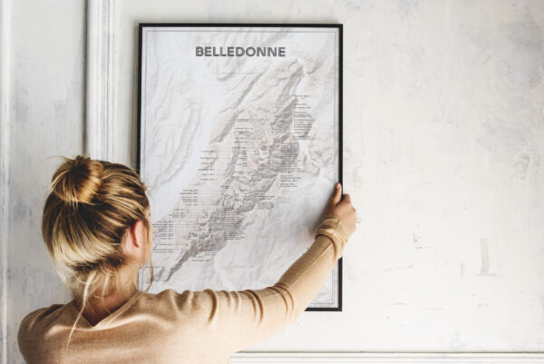 Poster de la carte de la chaîne de Belledonne dans un cadre noir tenu par une femme